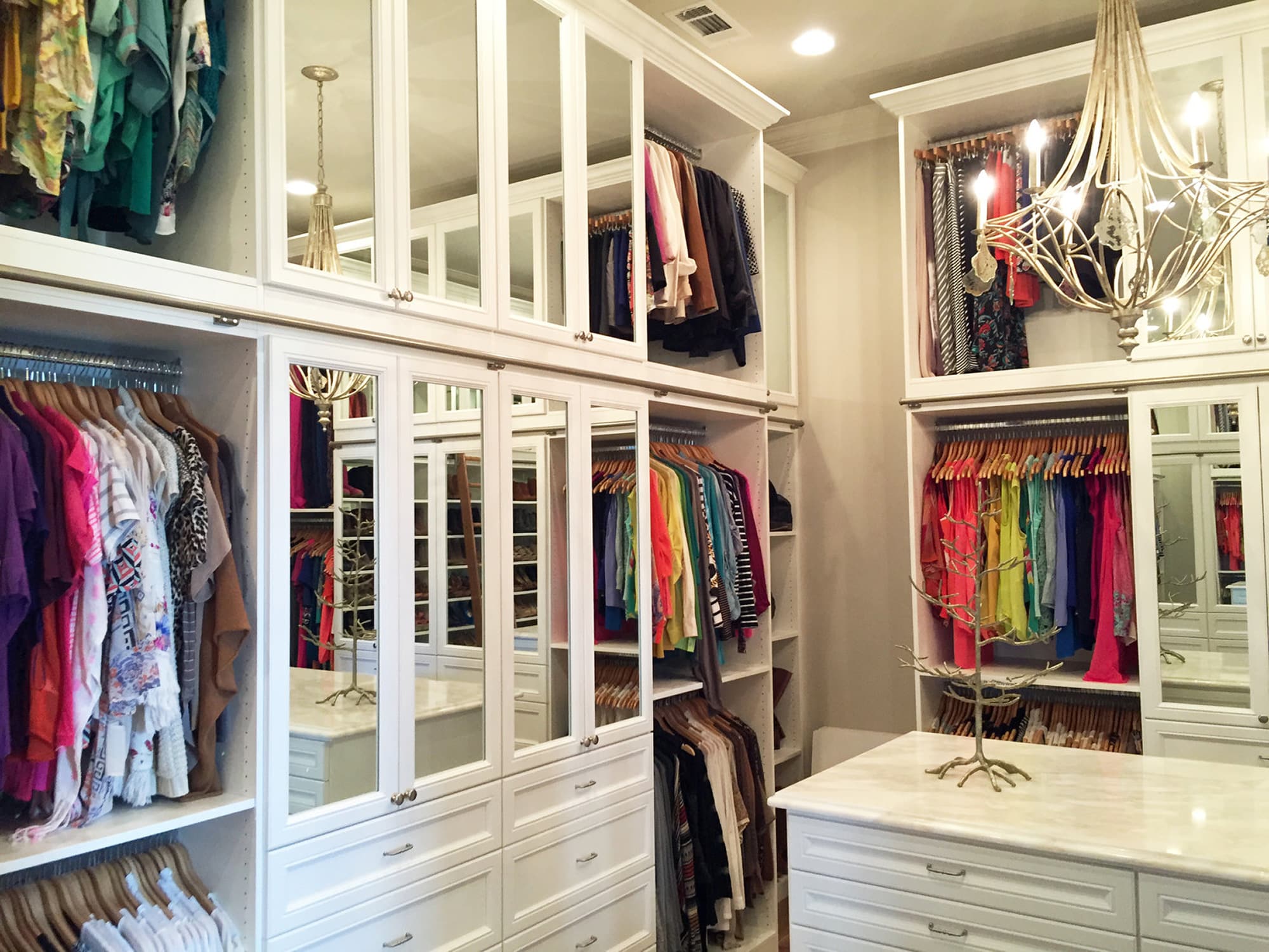 Beautiful closet remodel with white cabinets and drawers and large mirrors