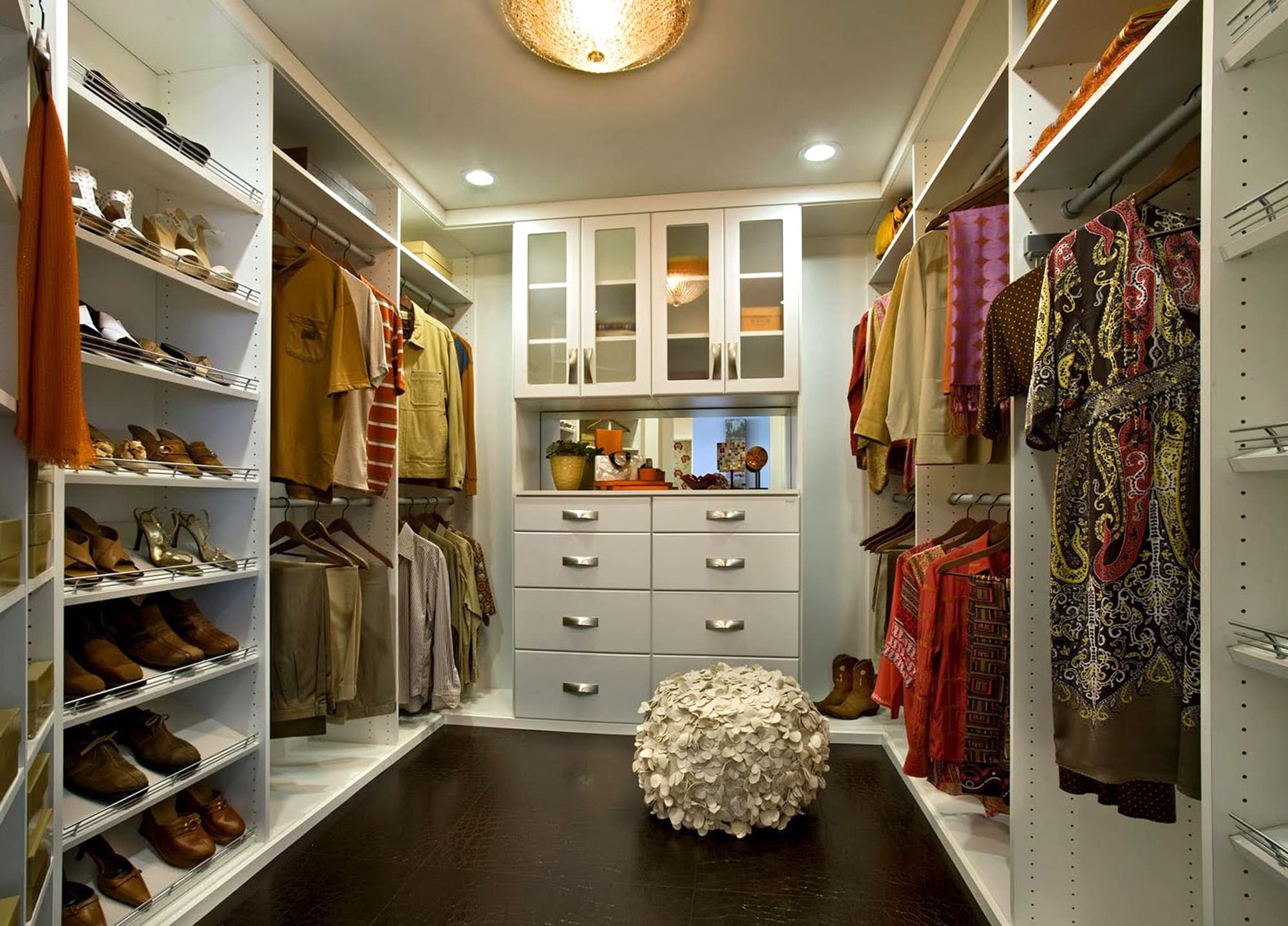 Large master closet with white cabinetry and shoe racks