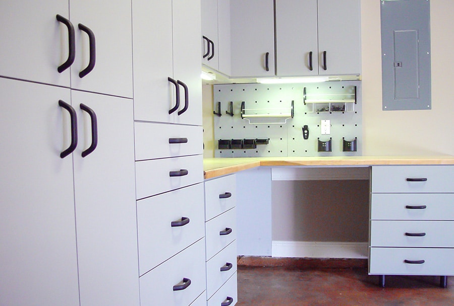 Garage with brand-new white drawers, cabinets, and slotwall
