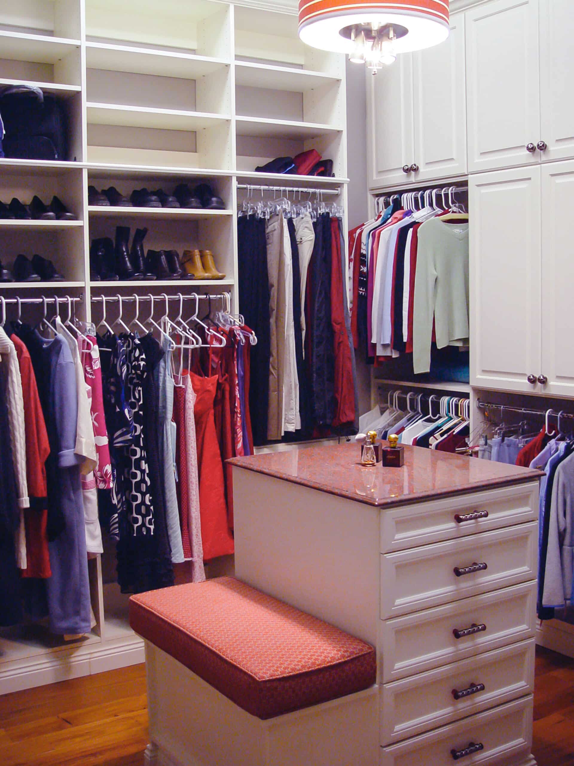 Custom closet with drawers, seating area, and organizers for clothing