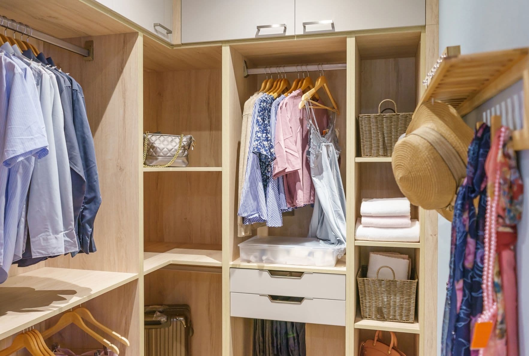 Walk-in closet with light wood and clothing on hangers
