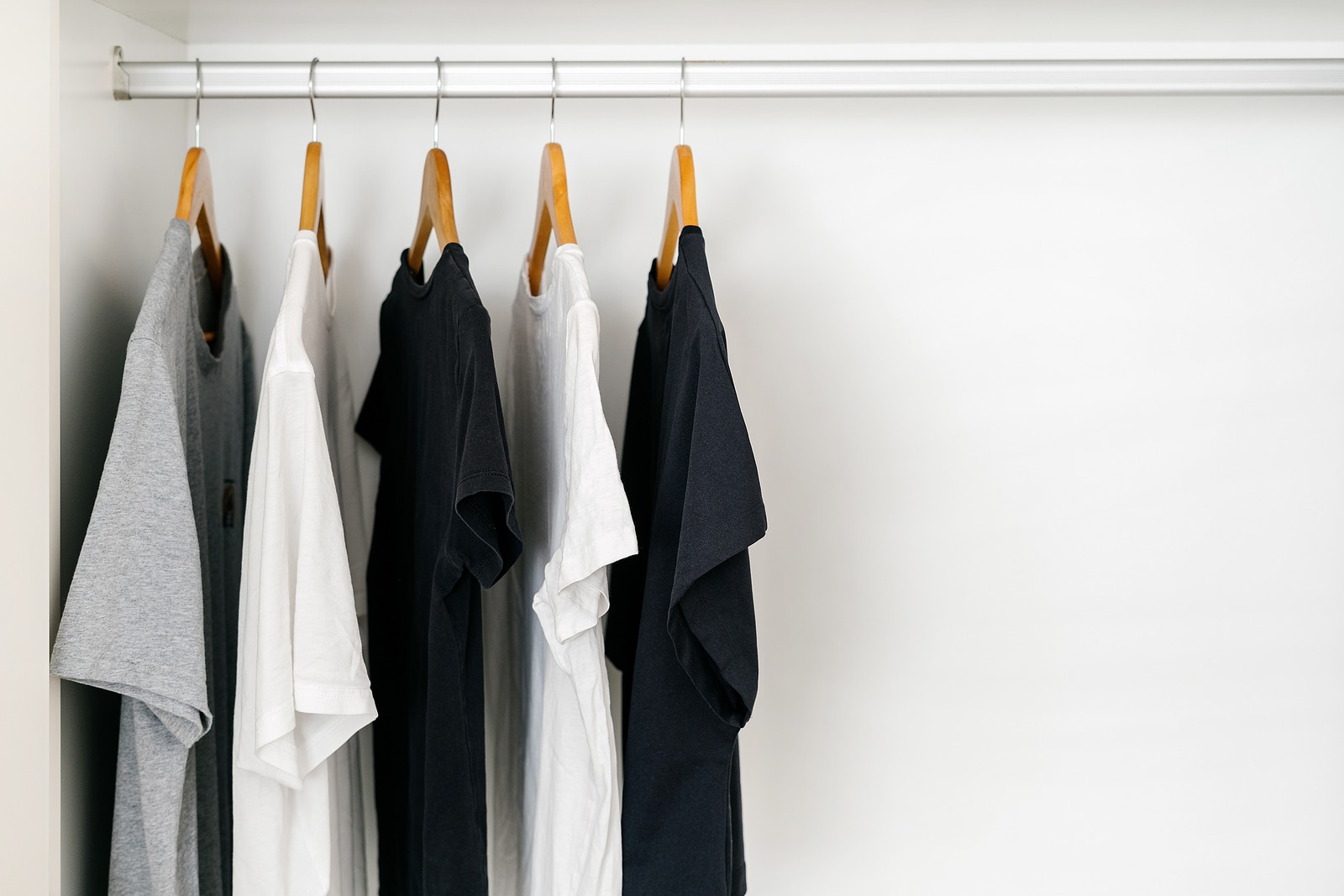 Shirts hanging on wooden hangers in a white closet