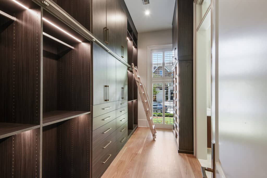 custom built closet with dark wood shelves and bright lights