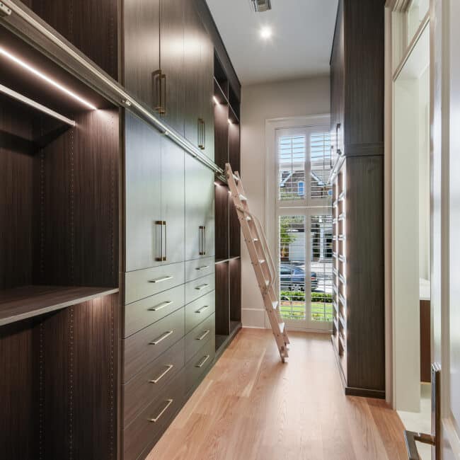 custom built closet with dark wood shelves and bright lights