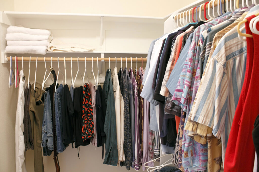 small closet with a minimal amount of brightly colored clothes